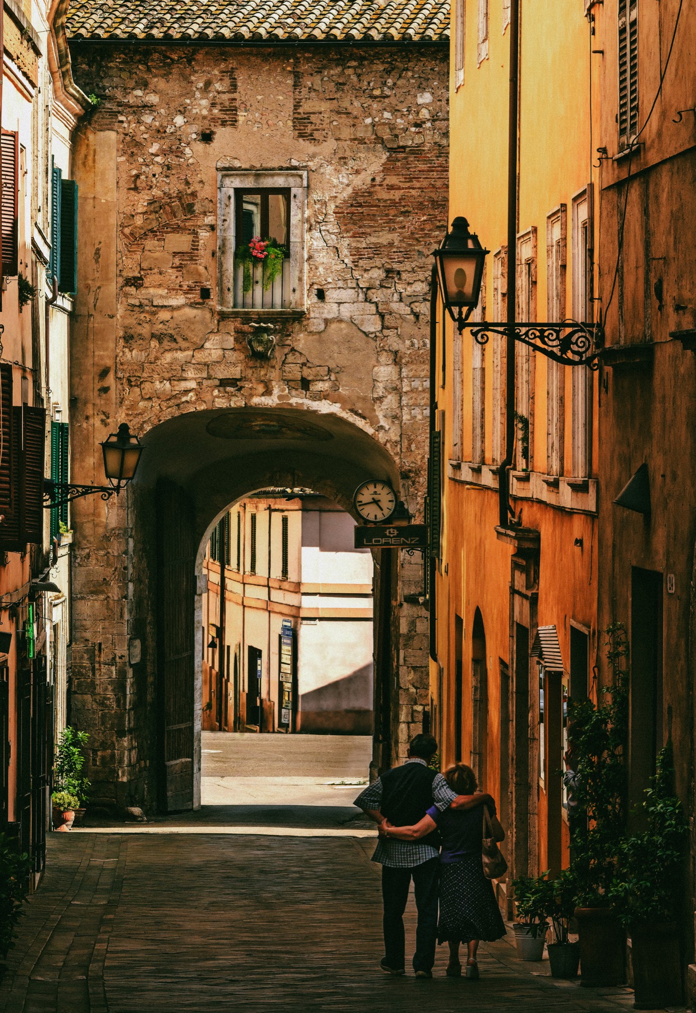 Two people talking under a stone archway in Italy